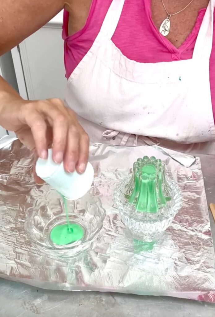 Pouring Mod Podge and paint mixture into the candle holders